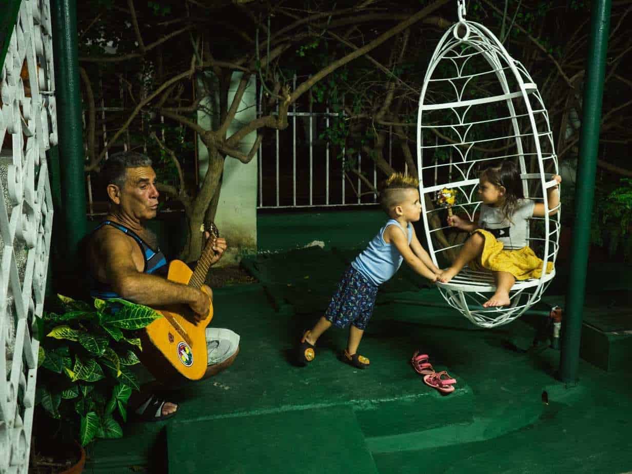 אישה מנגנת בגיטרה בזמן שילדים משחקים ברקע
